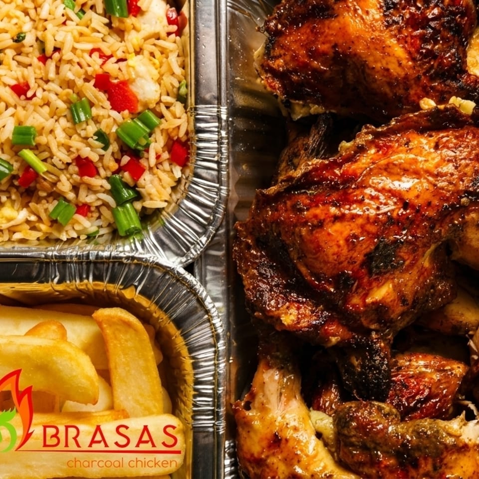 Las Brasas charcoal chicken, fried rice, and fries in foil containers.